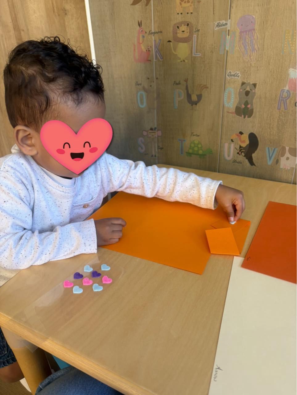 Enfant faisant une activité de pliage de papier coloré chez l'assistante maternelle